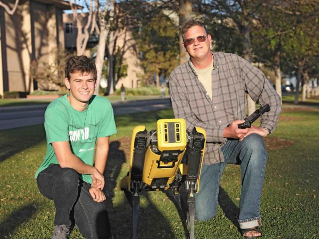 Spot poses with Bob Proebstel of FLIR Systems, Inc. and first year CCS computer scientist Nathan Wachholz, a current intern at FLIR
